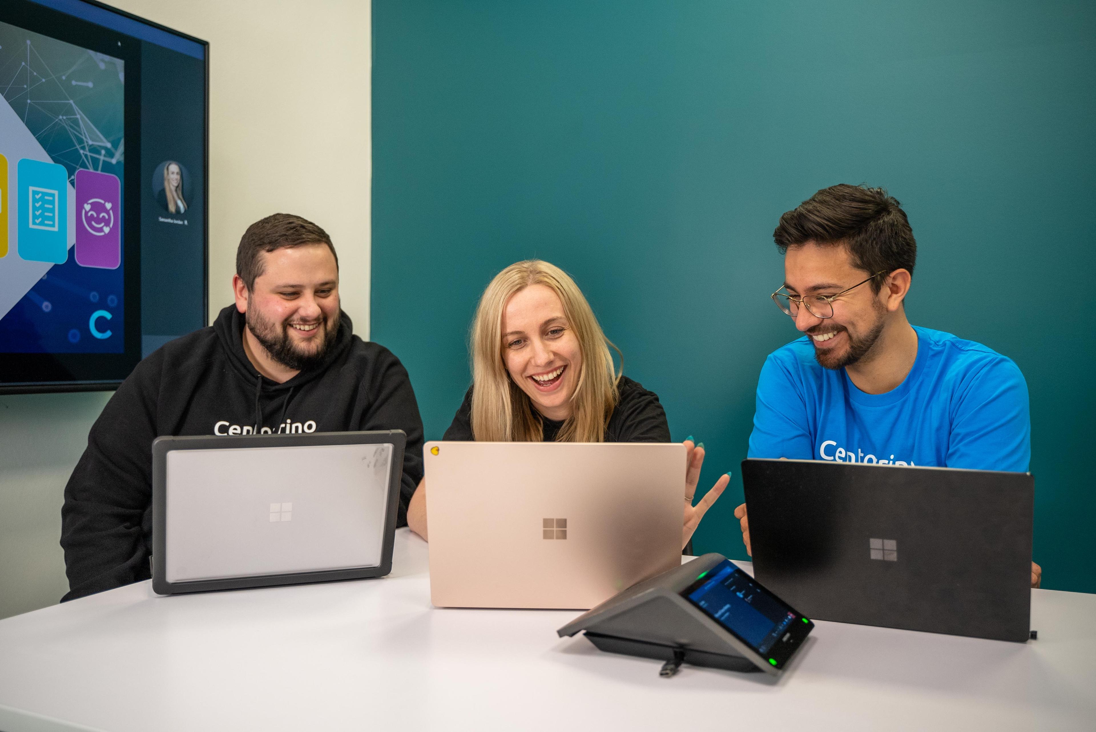 CT team members smiling while looking at their laptop screens